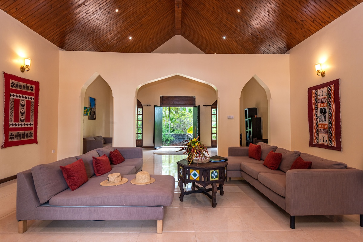 Living room with vaulted wood ceiling, triple arches and African textiles